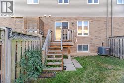 Brick and siding exterior featuring a wooden deck with stairs, a sliding glass door, and a ground-level window -