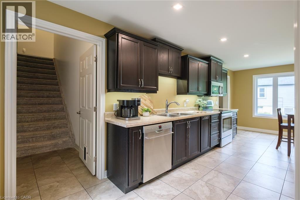 Contemporary kitchen featuring dark wood cabinetry, stainless steel appliances, light-toned countertops, and recessed lighting - 78 Oak Street, Simcoe, ON
