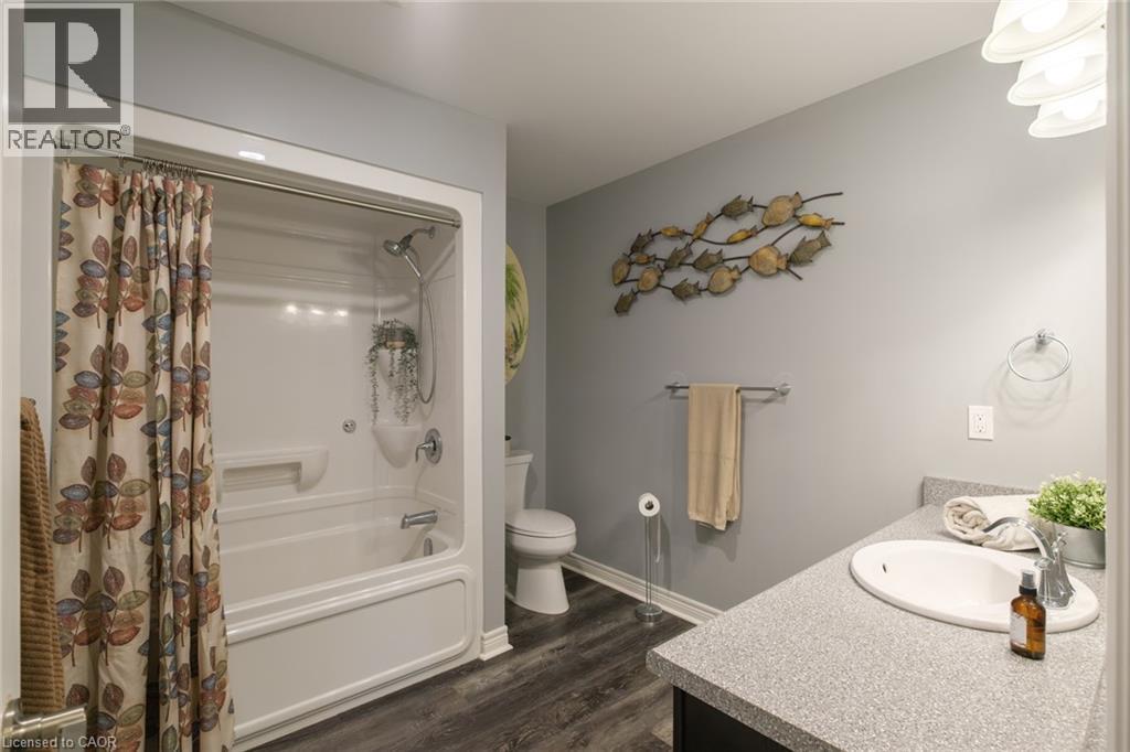 Tub/shower combination with a single-handle faucet, vanity with an integrated sink, and wood-finish flooring - 78 Oak Street, Simcoe, ON