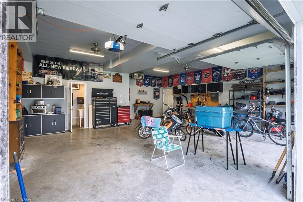 Attached garage with a concrete floor, built-in storage cabinetry, overhead lighting, and an overhead garage door - 78 Oak Street, Simcoe, ON