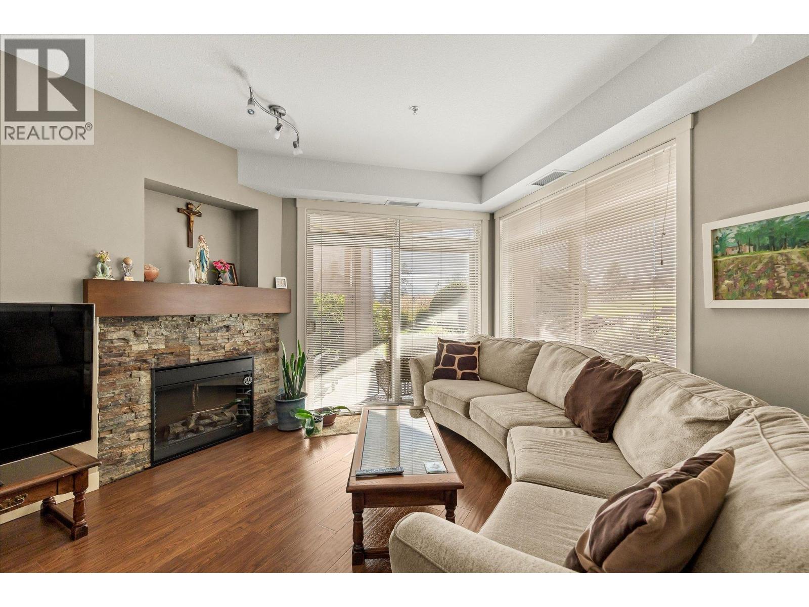 Cozy stone electric fireplace with a mantle. - 3545 Carrington Road Unit# 108, West Kelowna, BC