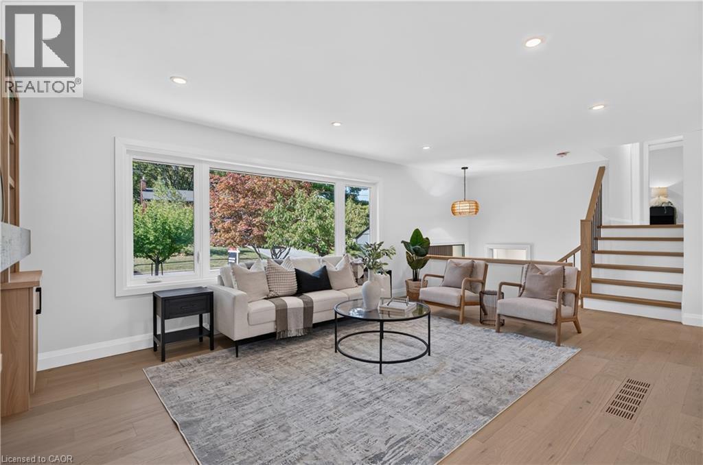 Expansive living area featuring wood-finish flooring, recessed lighting, and a large picture window - 3028 Eva Drive, Burlington, ON