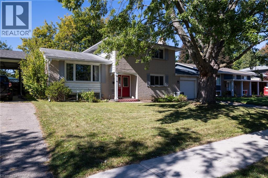 Split-level residence featuring a red entry door, attached single-car garage, and a covered carport - 52 Brier Park Road, Brantford, ON