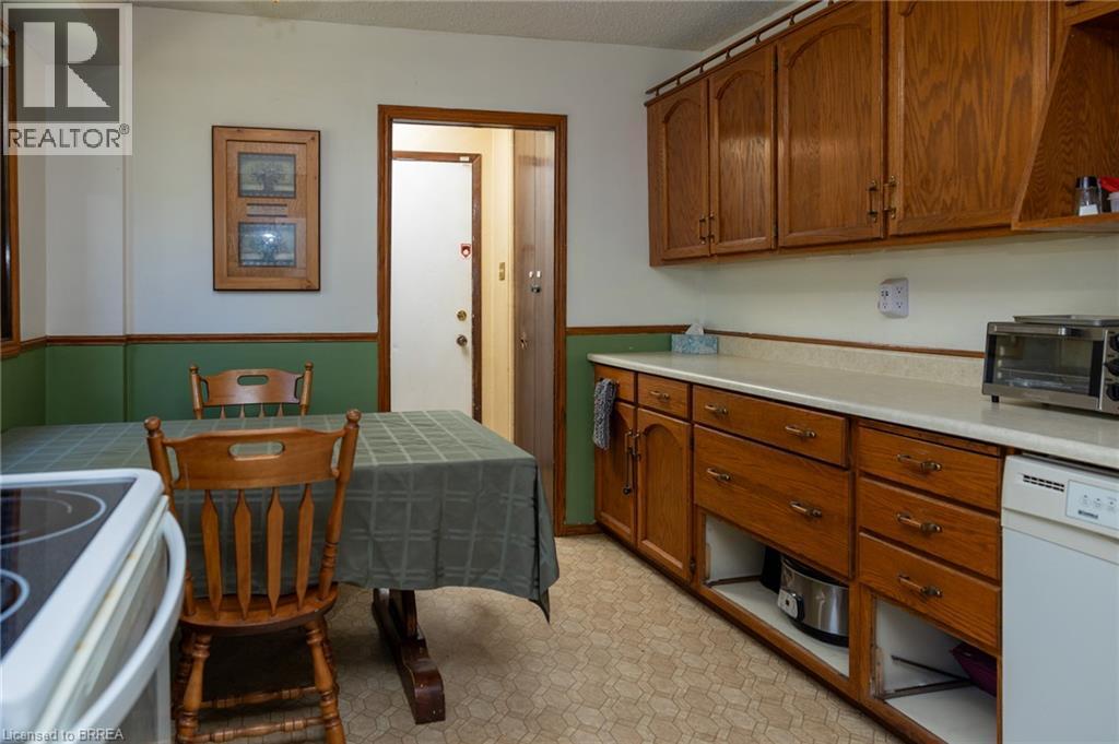 Kitchen featuring wood cabinetry, light-toned countertops, and vinyl flooring - 52 Brier Park Road, Brantford, ON