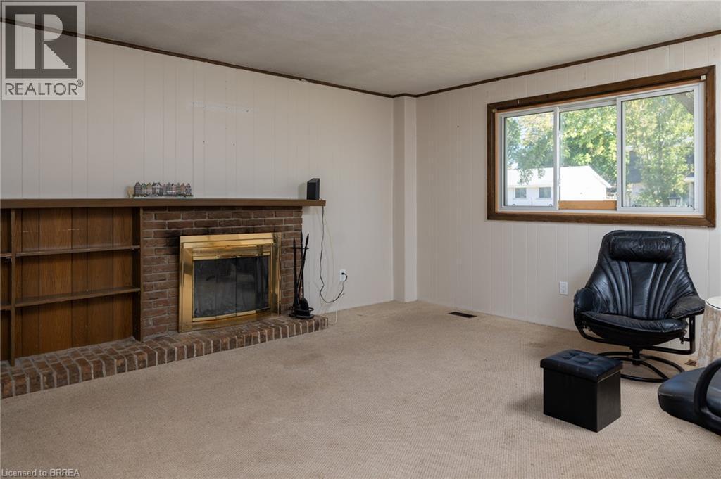Brick fireplace with an integrated wood-finish mantel and built-in shelving - 52 Brier Park Road, Brantford, ON