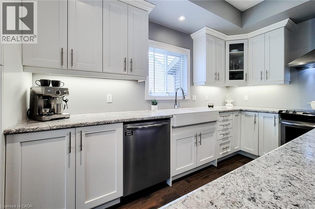White shaker cabinetry, stone countertops, stainless steel appliances, apron-front sink, and rich wood-finish flooring - 4274 Sixth Avenue, Niagara Falls, ON