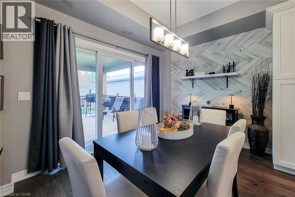 Wood-finish flooring, accent wall with a herringbone pattern, linear light fixture, built-in cabinetry, and sliding glass door - 4274 Sixth Avenue, Niagara Falls, ON