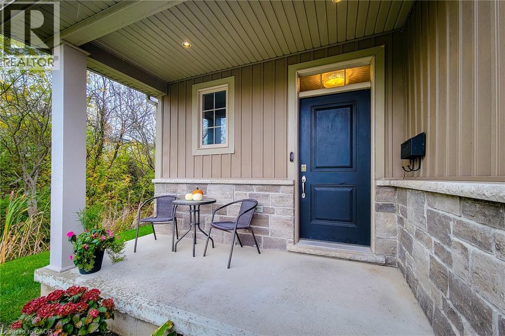 Covered front porch featuring a dark paneled entry door, stone and vertical siding exterior, and a single pane window - 4274 Sixth Avenue, Niagara Falls, ON