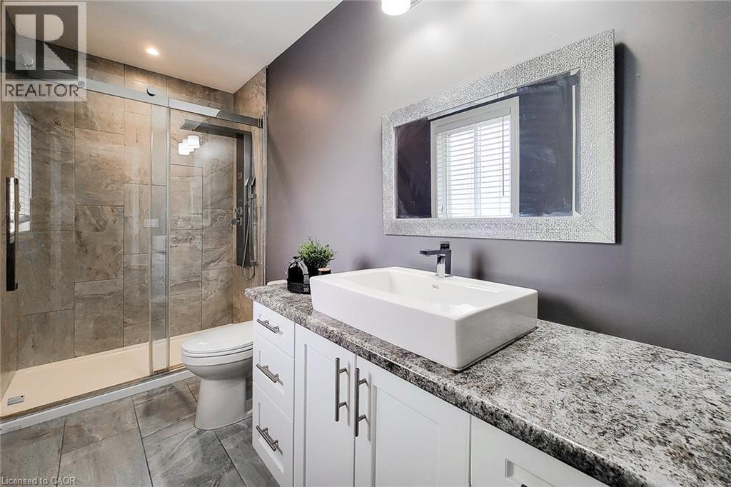 Glass-enclosed shower with full-height stone-look tile surround - 4274 Sixth Avenue, Niagara Falls, ON