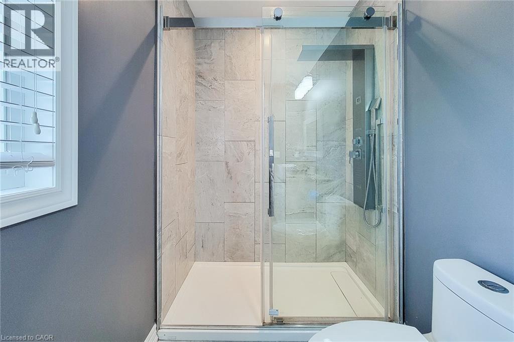 Glass-enclosed shower with a multi-function shower panel and light-toned tile surround - 4274 Sixth Avenue, Niagara Falls, ON