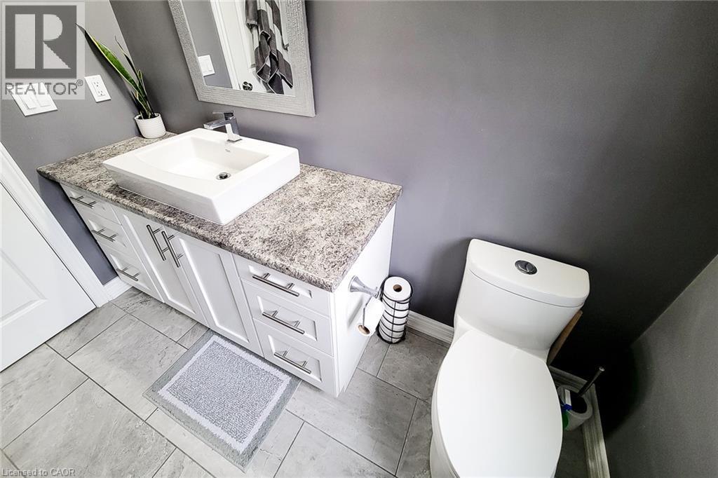 White vanity with brushed nickel hardware, rectangular vessel sink, patterned countertop, and light gray tile flooring - 4274 Sixth Avenue, Niagara Falls, ON