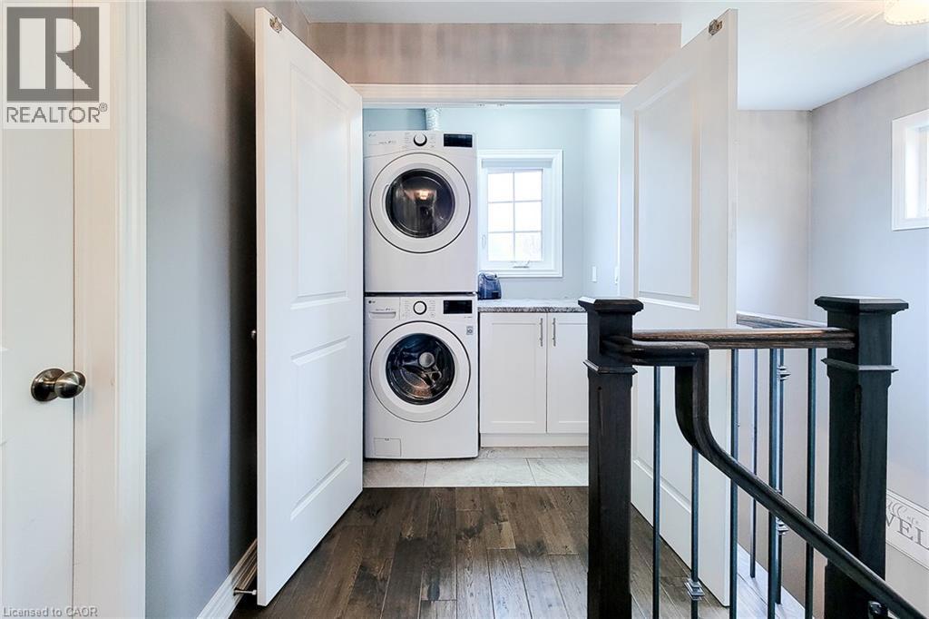 Dedicated laundry area with stacked appliances, white cabinetry, and a light-toned countertop - 4274 Sixth Avenue, Niagara Falls, ON