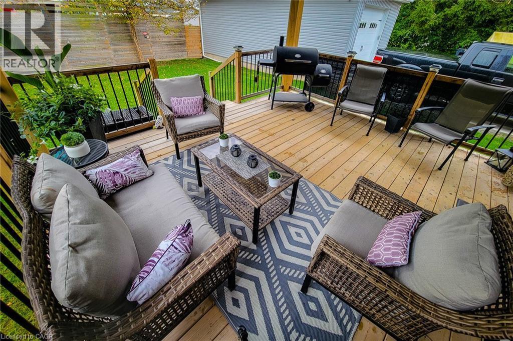 Expansive outdoor deck featuring wood flooring, black metal railing, and a fenced yard - 4274 Sixth Avenue, Niagara Falls, ON