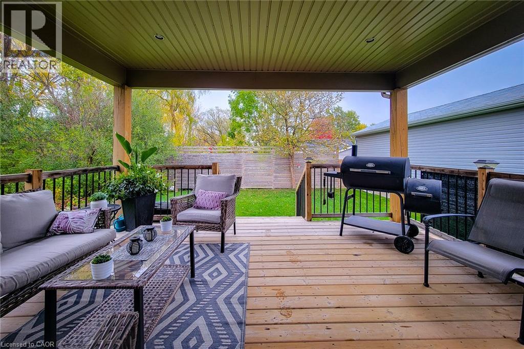 Covered wood deck with slatted ceiling, wood pillars, and black metal railings - 4274 Sixth Avenue, Niagara Falls, ON