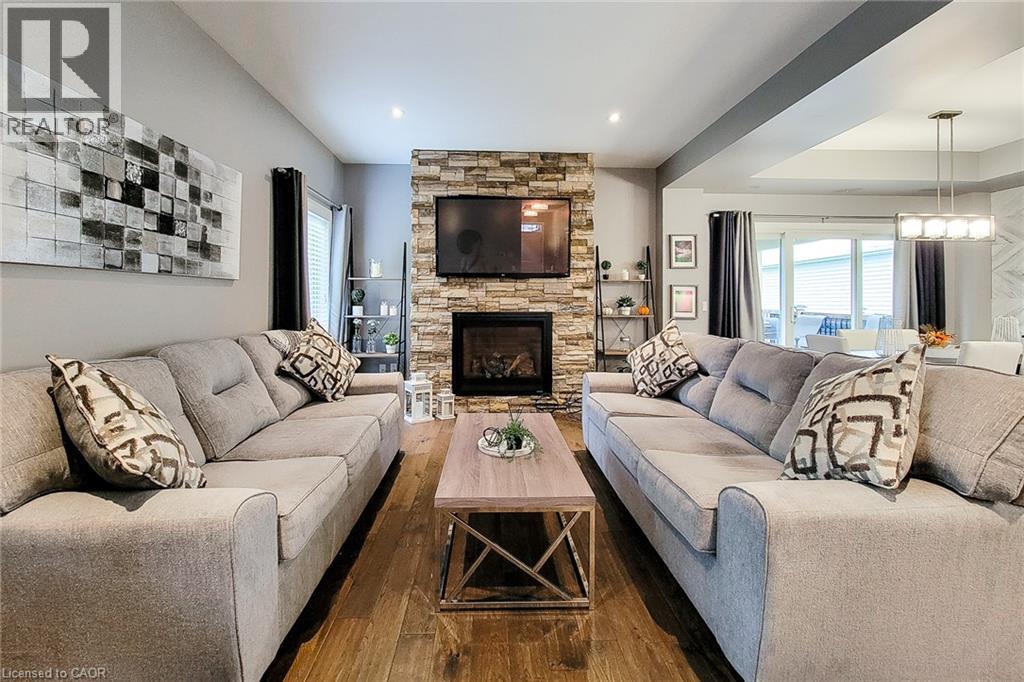 Wood-finish flooring, stone-clad fireplace, recessed lighting, and sliding glass door - 4274 Sixth Avenue, Niagara Falls, ON