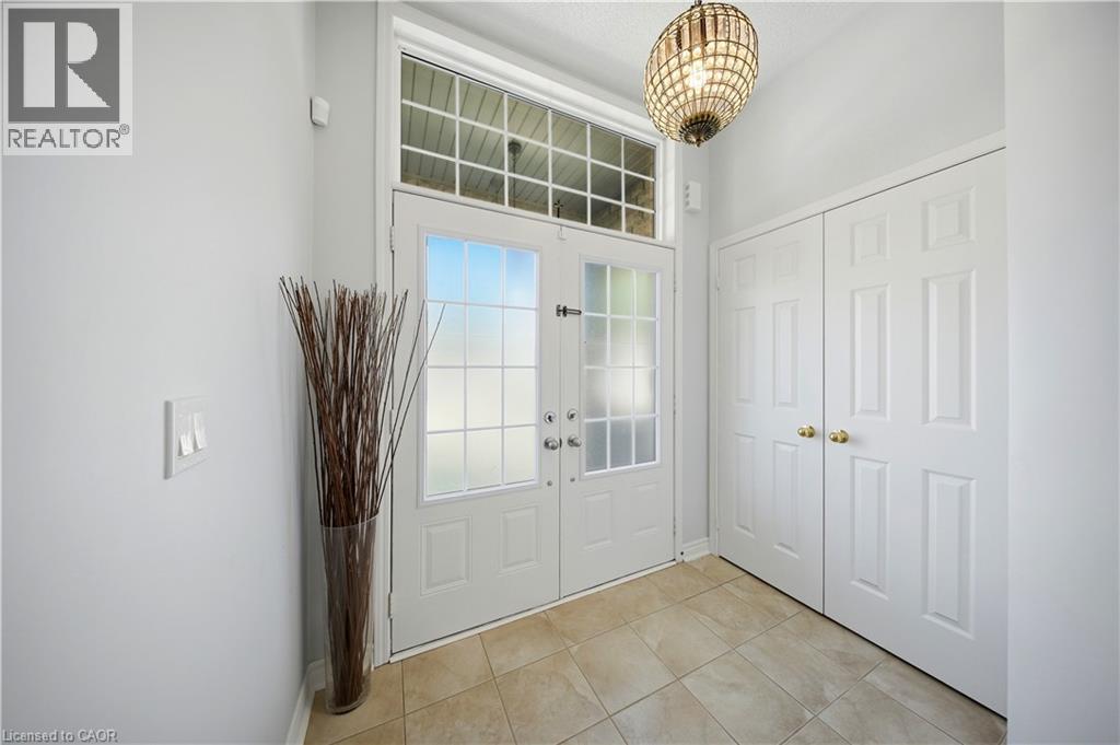 White double-entry doors with frosted glass panels, transom window, recessed lighting, and a decorative light fixture - 3352 Hiscott Avenue, Burlington, ON