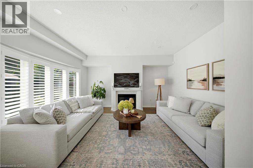 Recessed lighting, light-toned walls, wood-finish flooring, a white fireplace with a mantel, and plantation shutters - 3352 Hiscott Avenue, Burlington, ON
