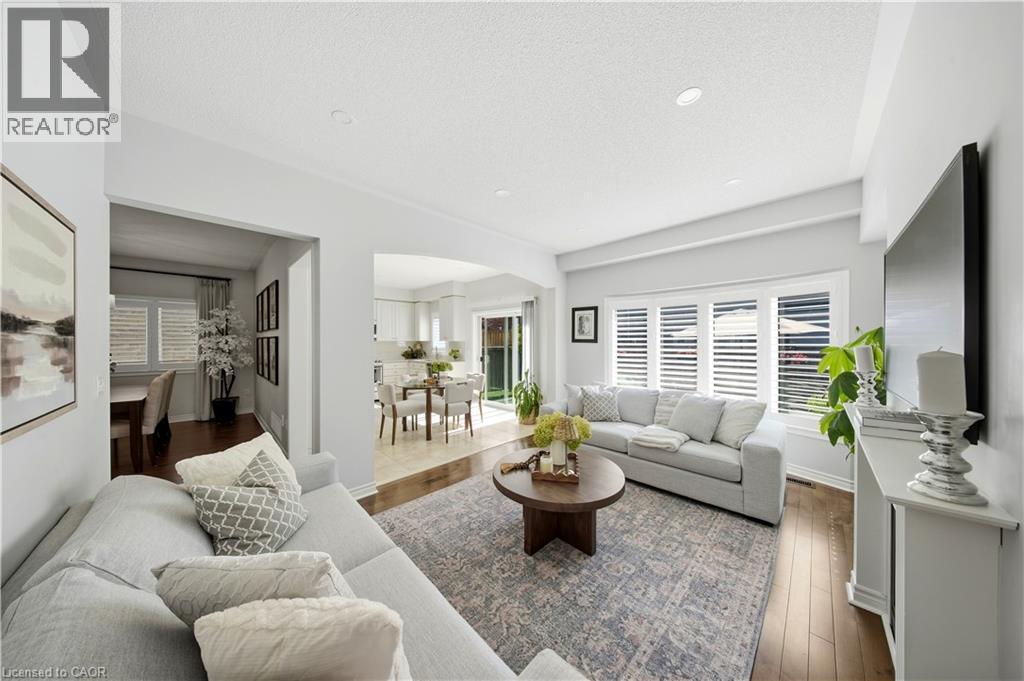 Recessed lighting illuminates the living area, featuring wood-finish flooring and crown molding - 3352 Hiscott Avenue, Burlington, ON