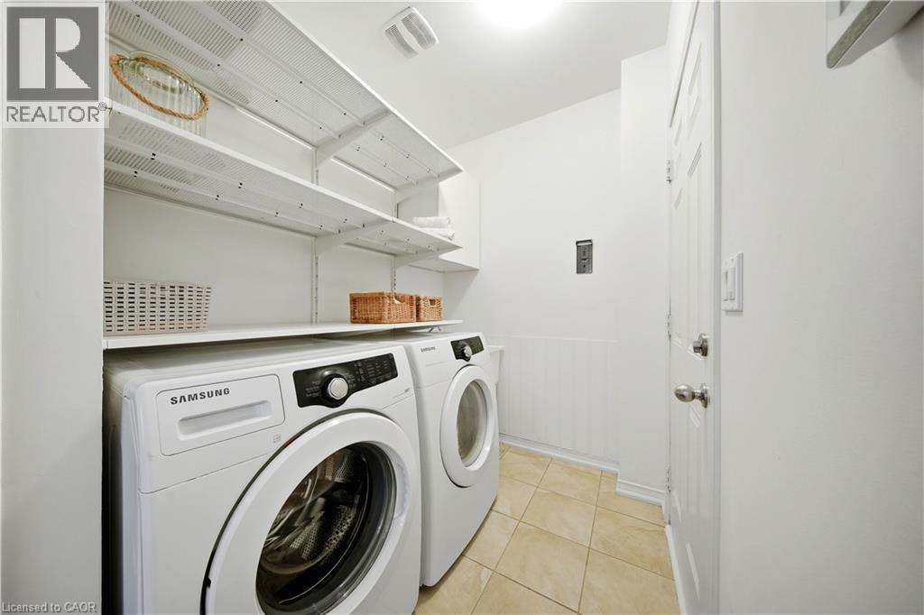 Laundry area featuring white walls, tile flooring, and integrated shelving - 3352 Hiscott Avenue, Burlington, ON