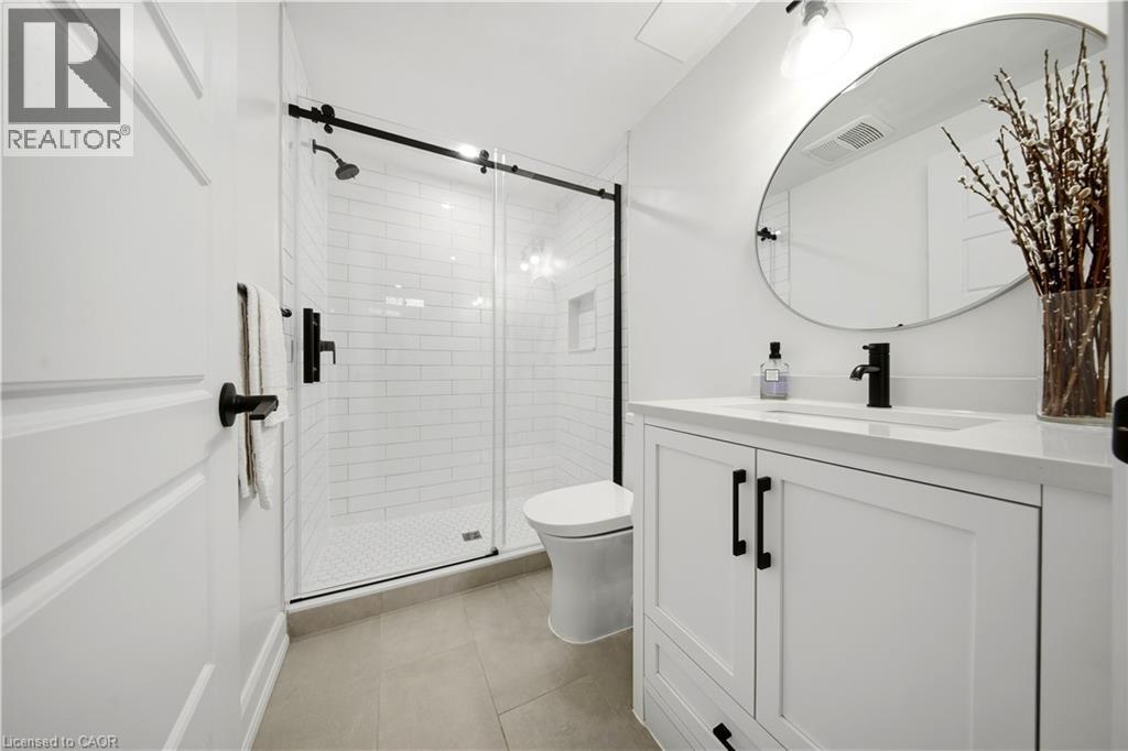 White shaker vanity with a single basin sink and black hardware - 3352 Hiscott Avenue, Burlington, ON
