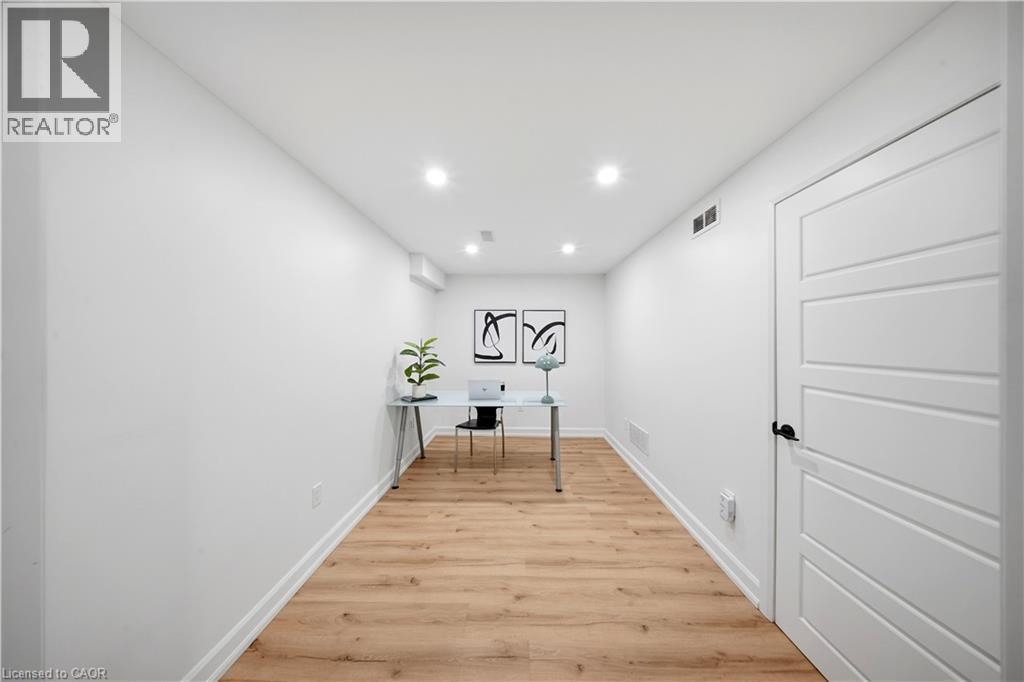 Wood-finish flooring, recessed lighting, white walls, and a four-panel interior door with matte black hardware - 3352 Hiscott Avenue, Burlington, ON