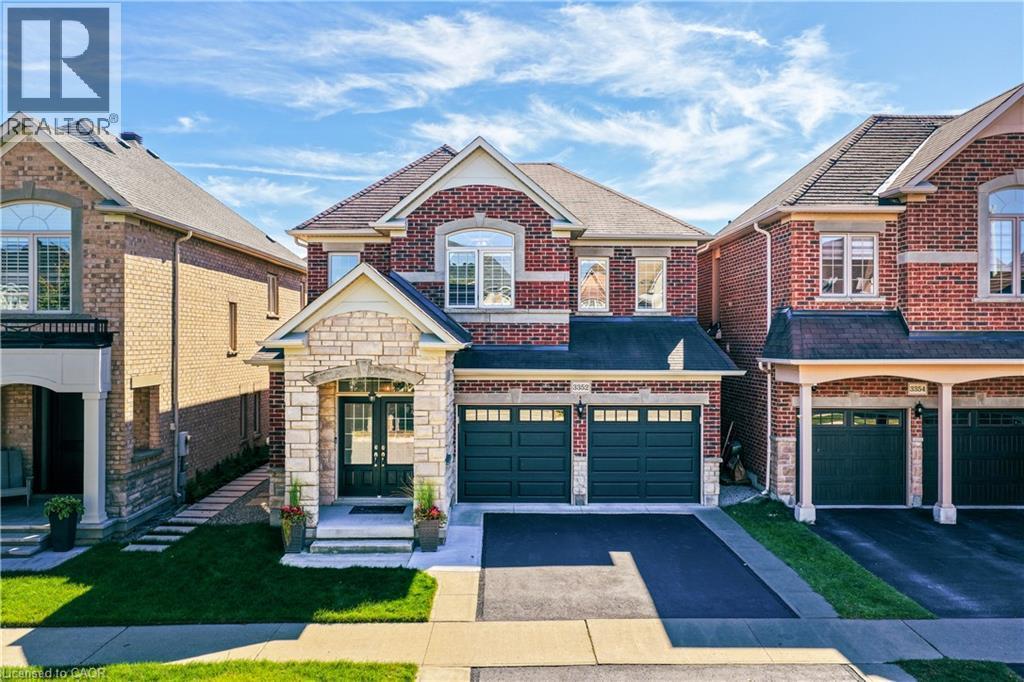 Brick and stone facade, double-door entry, arched windows, two-car garage, and paved driveway - 3352 Hiscott Avenue, Burlington, ON