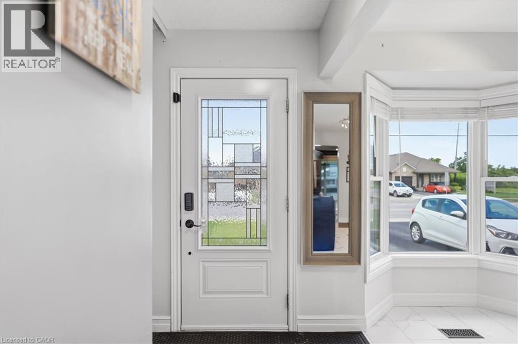 Entryway featuring a white door with decorative glass, a digital keypad lock, and a bay window - 4804 John Street, Beamsville, ON
