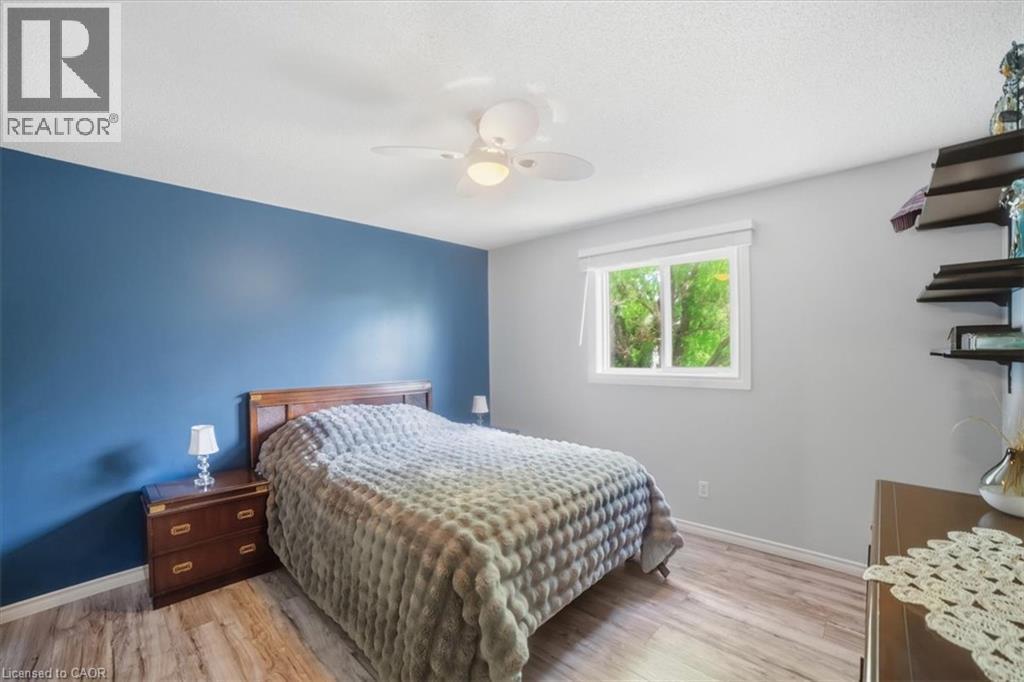 Wood-finish flooring, a window with a roller shade, and a ceiling fan with integrated lighting - 4804 John Street, Beamsville, ON