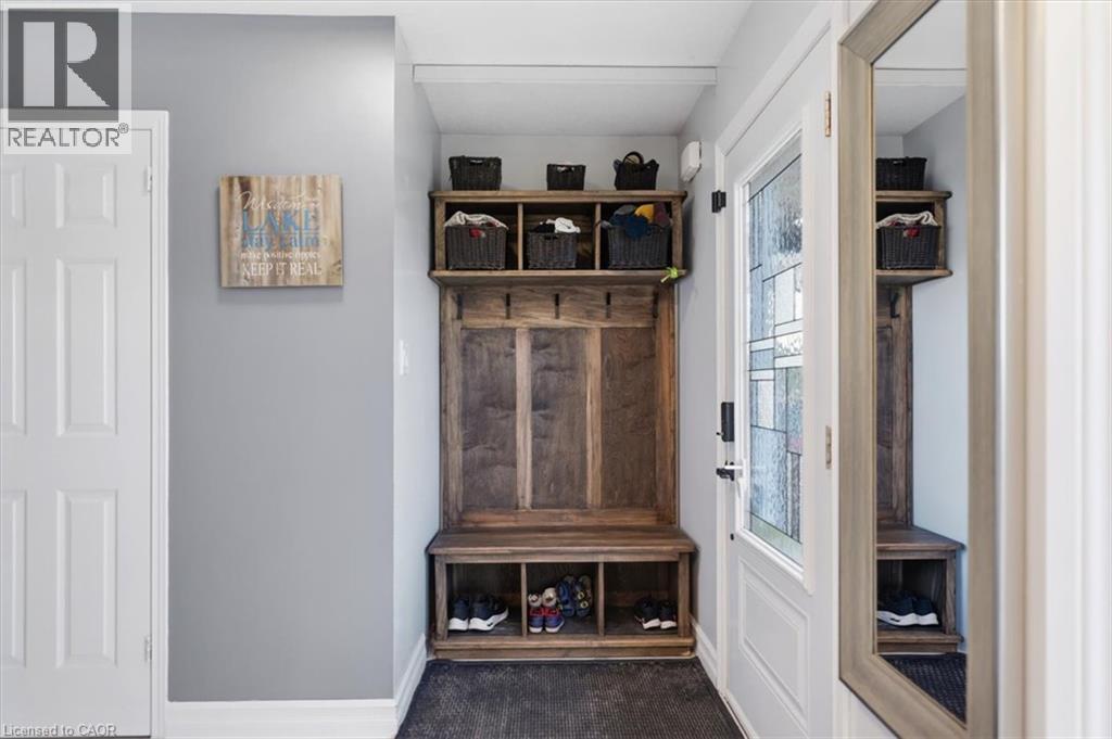 Built-in wood-finish mudroom storage unit with shelving and hooks - 4804 John Street, Beamsville, ON