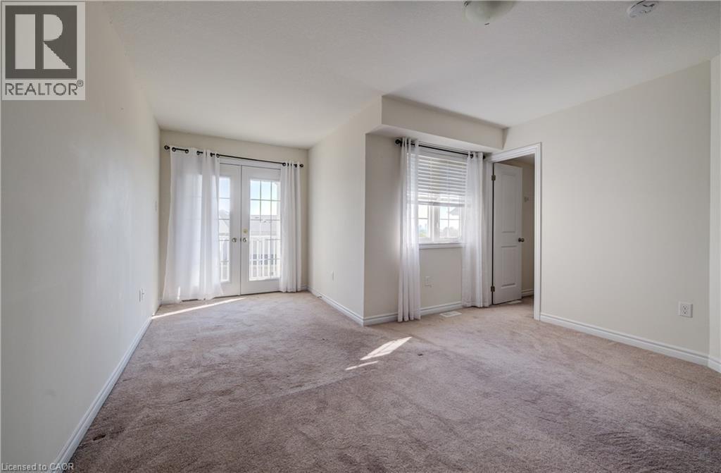 Carpeted room featuring a double French door balcony entry, a single window with blinds, and white trim - 403 Westwood Drive Unit# 59, Kitchener, ON