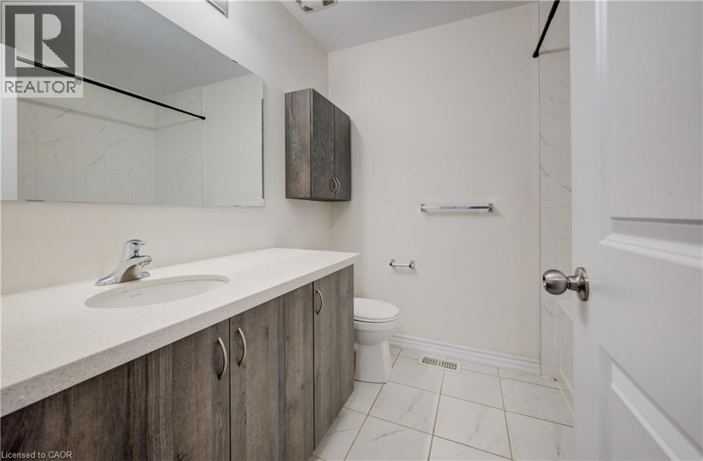 Bathroom featuring a wood-finish vanity with an integrated sink and chrome faucet, a coordinating wall-mounted storage cabinet, and white tile flooring - 403 Westwood Drive Unit# 59, Kitchener, ON