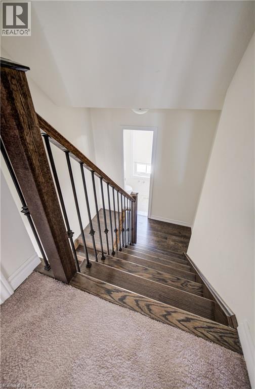 Staircase featuring wood-finish treads, iron balusters, and a rich wood-finish handrail - 403 Westwood Drive Unit# 59, Kitchener, ON
