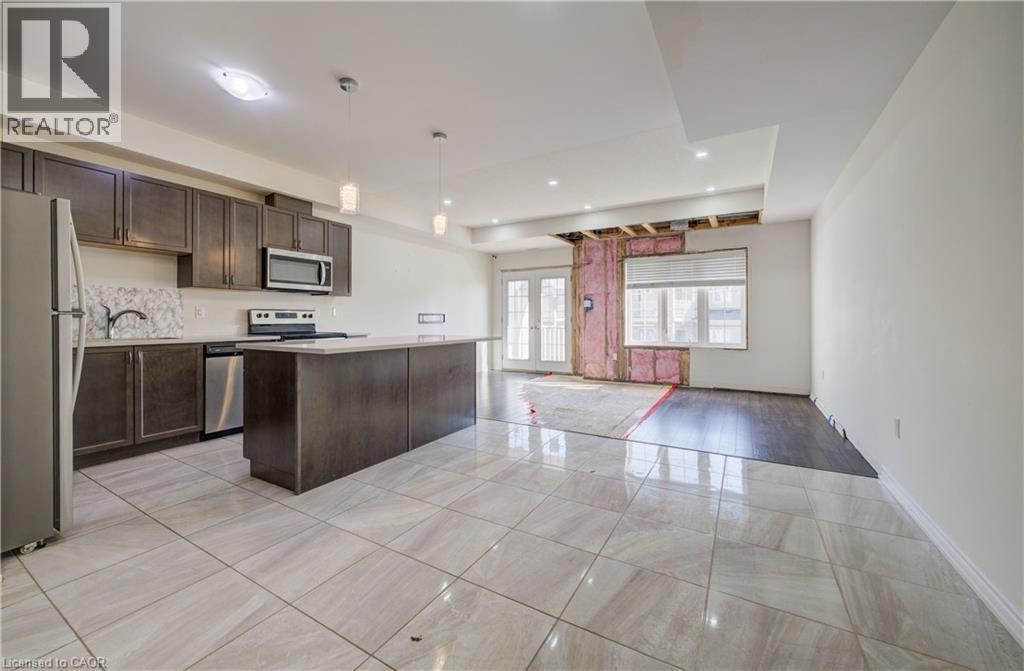 Kitchen featuring dark wood-finish cabinetry, stainless steel appliances, a white countertop, and a kitchen island - 403 Westwood Drive Unit# 59, Kitchener, ON