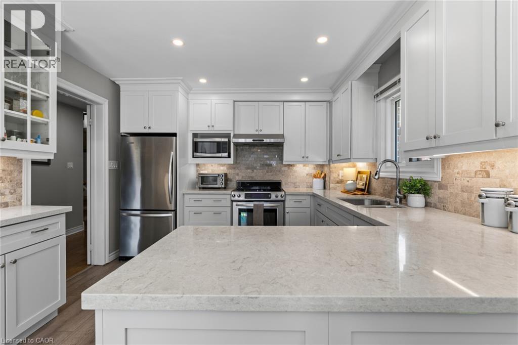 Kitchen featuring white shaker-style cabinetry, light-toned countertops, stainless steel appliances, a tile backsplash, and recessed lighting - 1610 Heathside Crescent, Pickering, ON