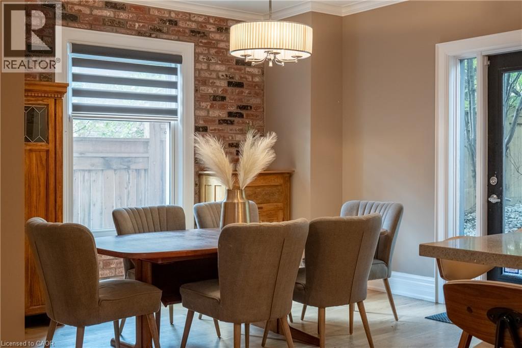 Exposed brick accent wall, crown molding, drum pendant light fixture, and wood-finish flooring - 283 Plains Road W, Burlington, ON