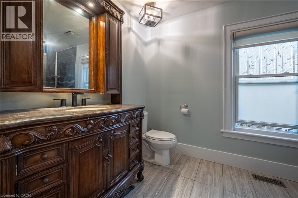 Ornate wood vanity with a stone countertop and integrated sink - 283 Plains Road W, Burlington, ON