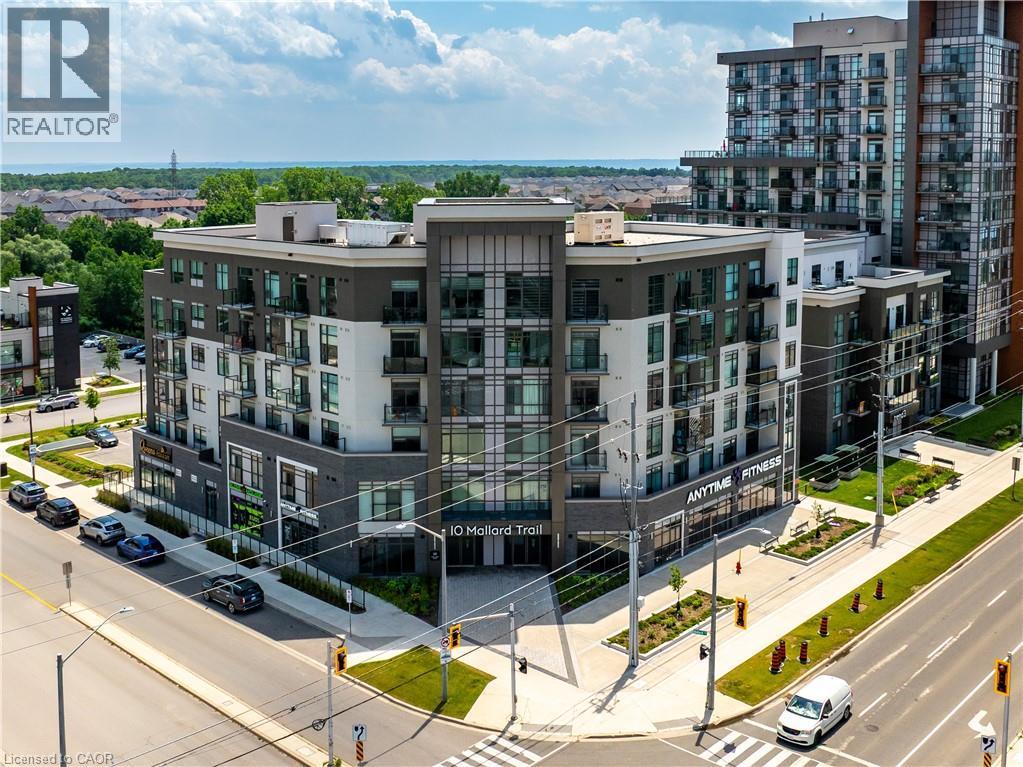 Modern multi-story building featuring balconies, large windows, and a prominent commercial storefront - 10 Mallard Trail Unit# 237, Waterdown, ON