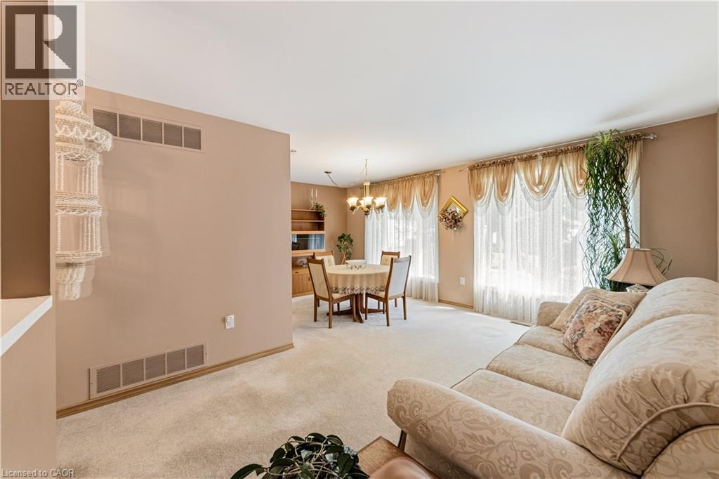 Open concept living and dining areas featuring neutral wall tones, light-toned carpeting, and a dining space - 450 Brigadoon Drive, Hamilton, ON