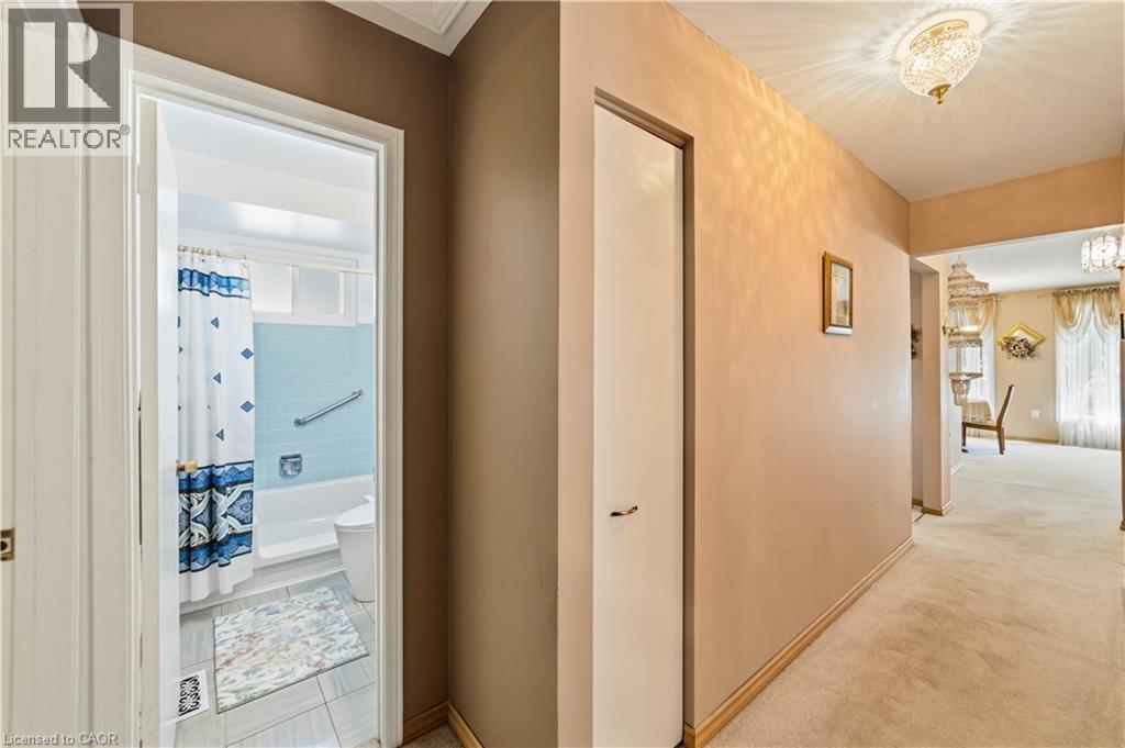 Hallway with linen closet and light-toned wall paint, 3 piece bathroom, original tiling still in great shape, vinyl flooring - 450 Brigadoon Drive, Hamilton, ON