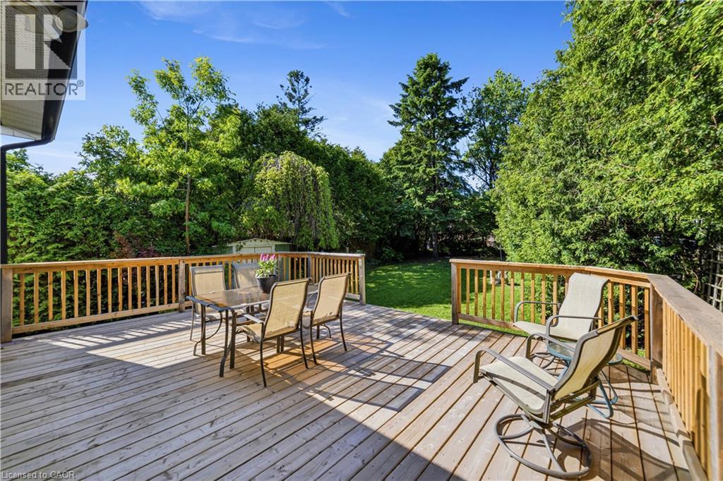 Spacious newer wooden deck with natural wood railing, overlooking a manicured lawn and mature perimeter trees - 450 Brigadoon Drive, Hamilton, ON
