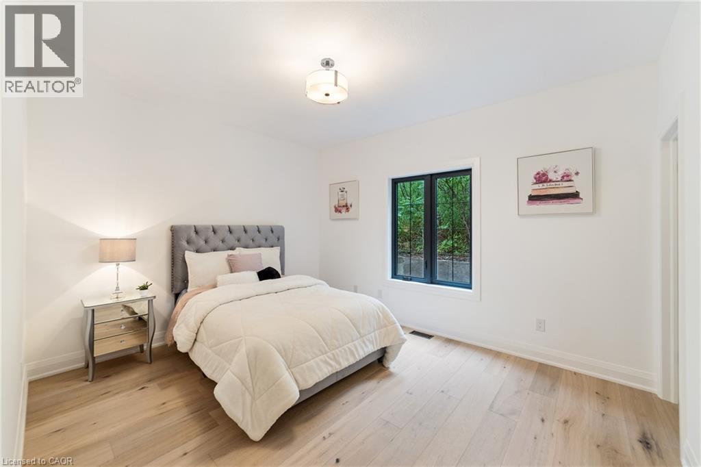 Bedroom featuring luxury flooring, large window looking onto greenspace and custom cabinetry in walk-in closet - 515 Hamilton Drive, Ancaster, ON