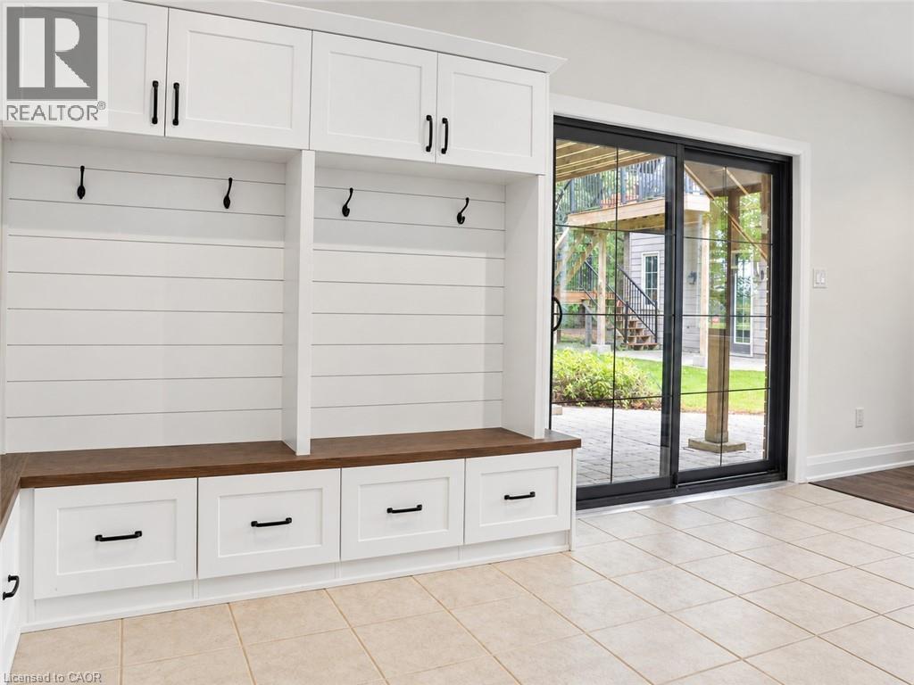 Built-in white cabinetry with matte black hardware, wood-finish bench seating, three storage drawers, and three coat hooks - 515 Hamilton Drive, Ancaster, ON