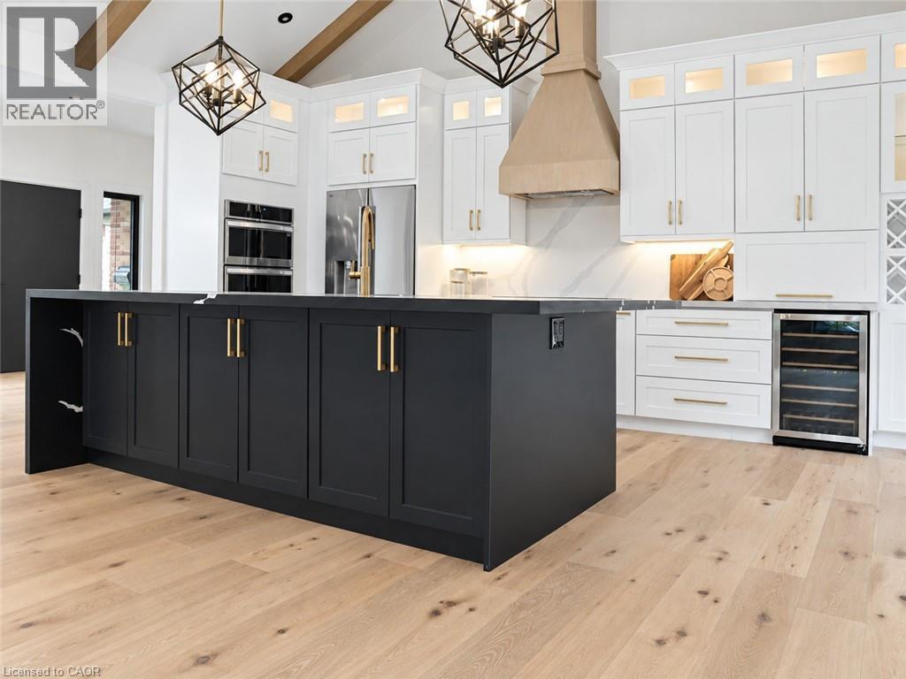 Kitchen with all new stainless-steel appliances, custom white cabinetry with additional cabinets in island, induction stove top, luxury flooring, garden doors to the right, beam ceiling, display cabin - 515 Hamilton Drive, Ancaster, ON