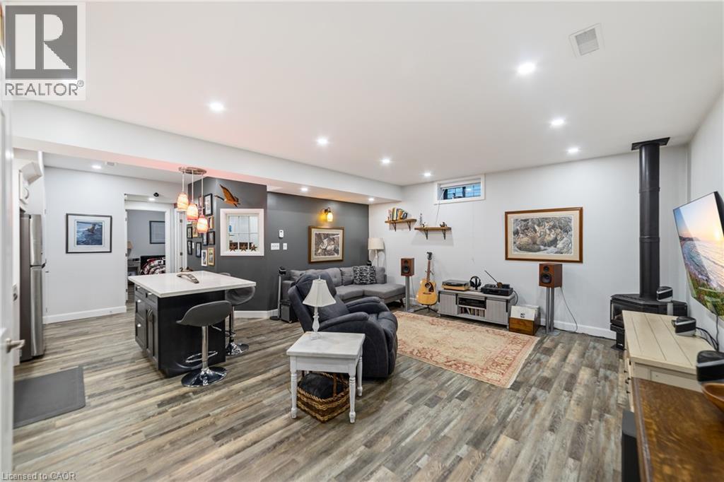 Spacious room featuring wood-finish flooring, recessed lighting, and a dark-toned kitchen island with a light-colored countertop - 515 Hamilton Drive, Ancaster, ON