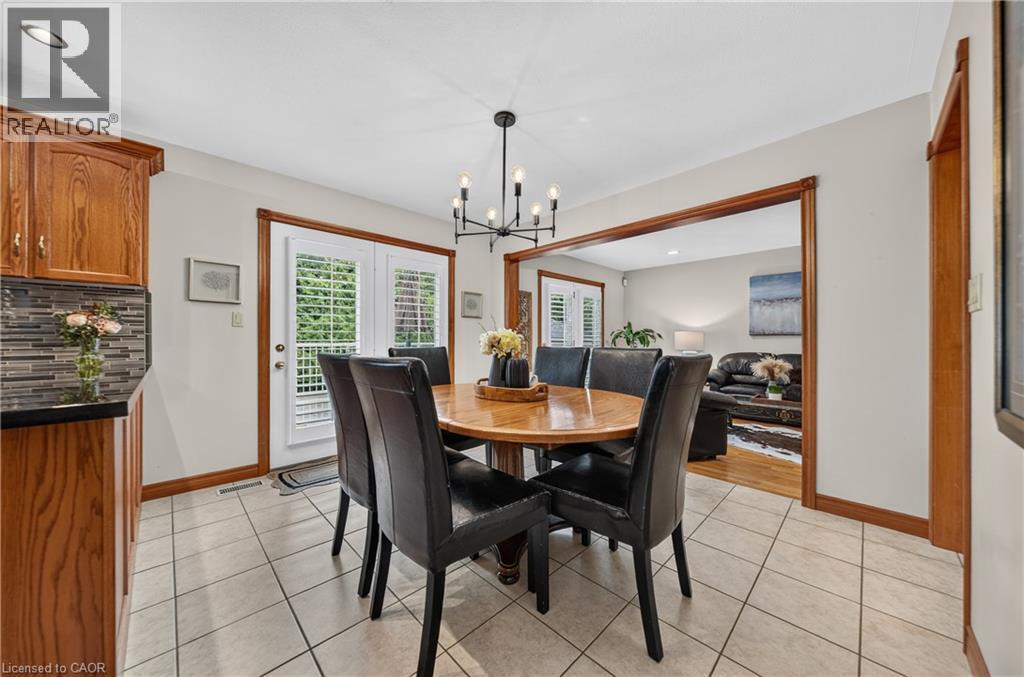 Tile flooring with a dark grout, wood cabinetry, dark countertops, and a mosaic tile backsplash - 52 Archwood Crescent, Cambridge, ON