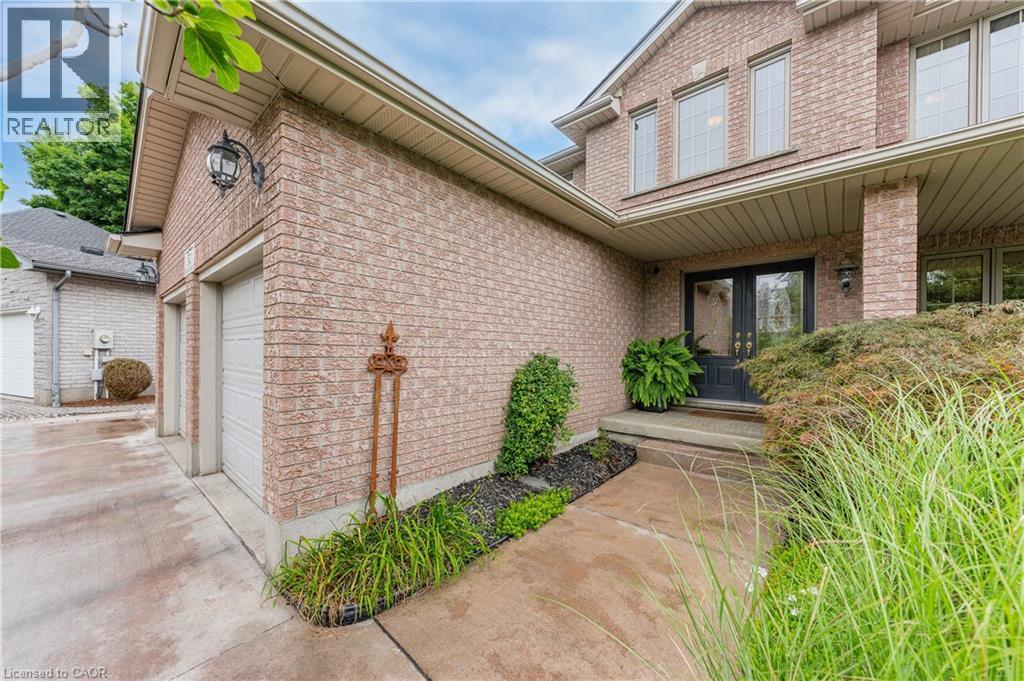 Brick exterior with two-car garage, covered entry, double entry doors, and landscaping - 52 Archwood Crescent, Cambridge, ON