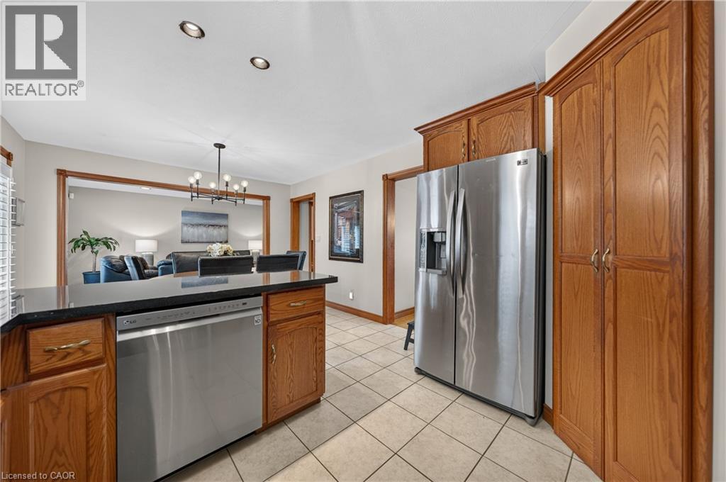 Kitchen featuring tile flooring, wood-finish cabinetry, stainless steel dishwasher, stainless steel refrigerator, and recessed lighting - 52 Archwood Crescent, Cambridge, ON