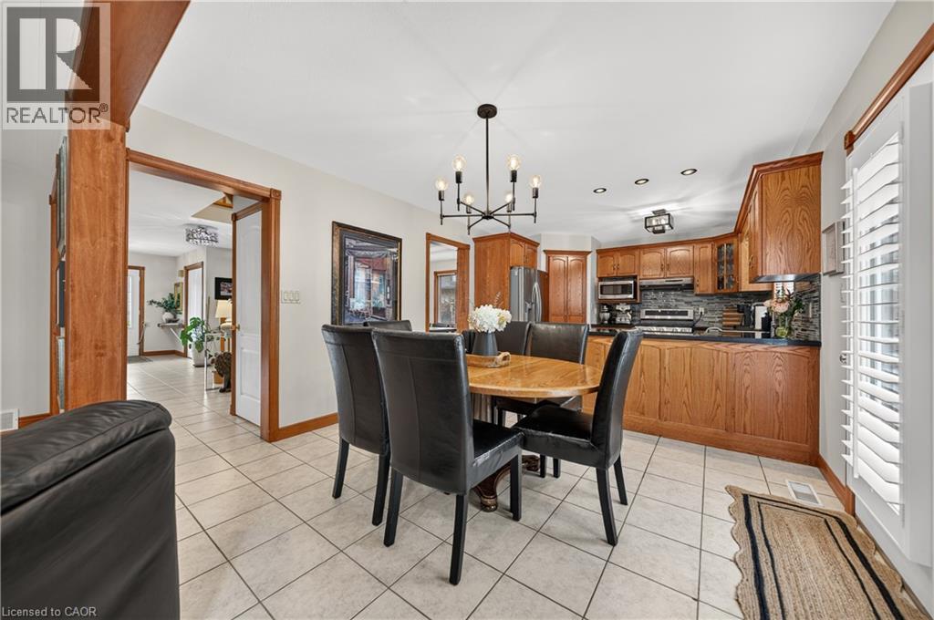 Integrated kitchen and dining area featuring ceramic tile flooring, wood cabinetry, built-in stainless steel appliances, and ceiling-mounted lighting - 52 Archwood Crescent, Cambridge, ON