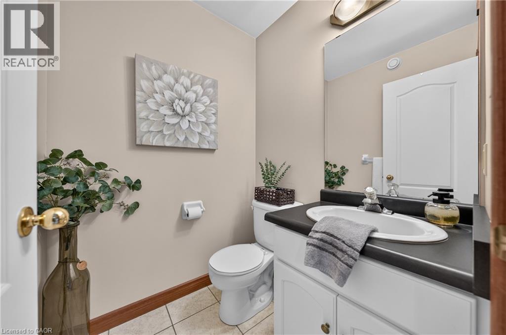 White vanity with integrated sink, dark countertop, and large wall-mounted mirror - 52 Archwood Crescent, Cambridge, ON