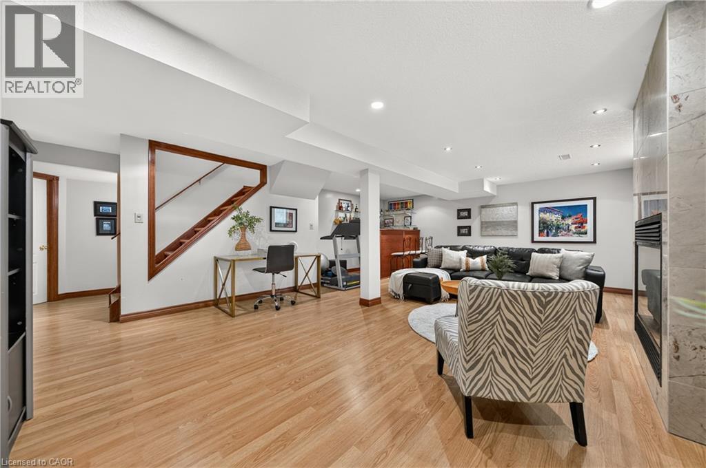 Recessed lighting, wood-finish flooring, a wood-trimmed staircase, a built-in wet bar, and a fireplace with a stone surround - 52 Archwood Crescent, Cambridge, ON